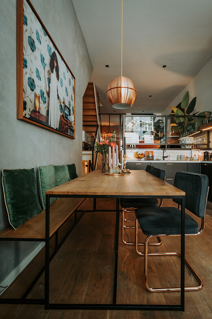 Dining room with wooden bench, velvet cushions, industrial dining table and copper pendant light