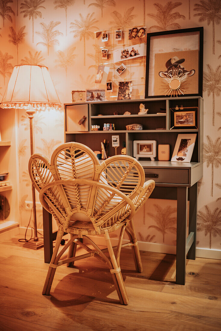 Desk corner with rattan chair and retro-style palm wallpaper