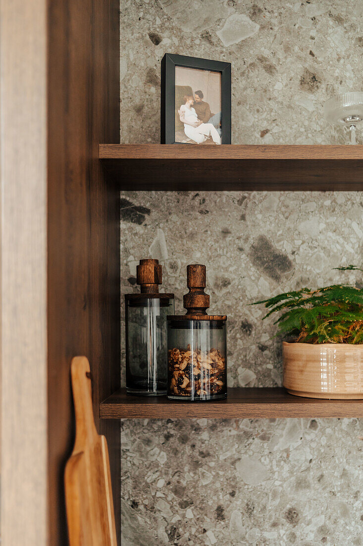 Open kitchen shelf with spice jars with stone wall in the background