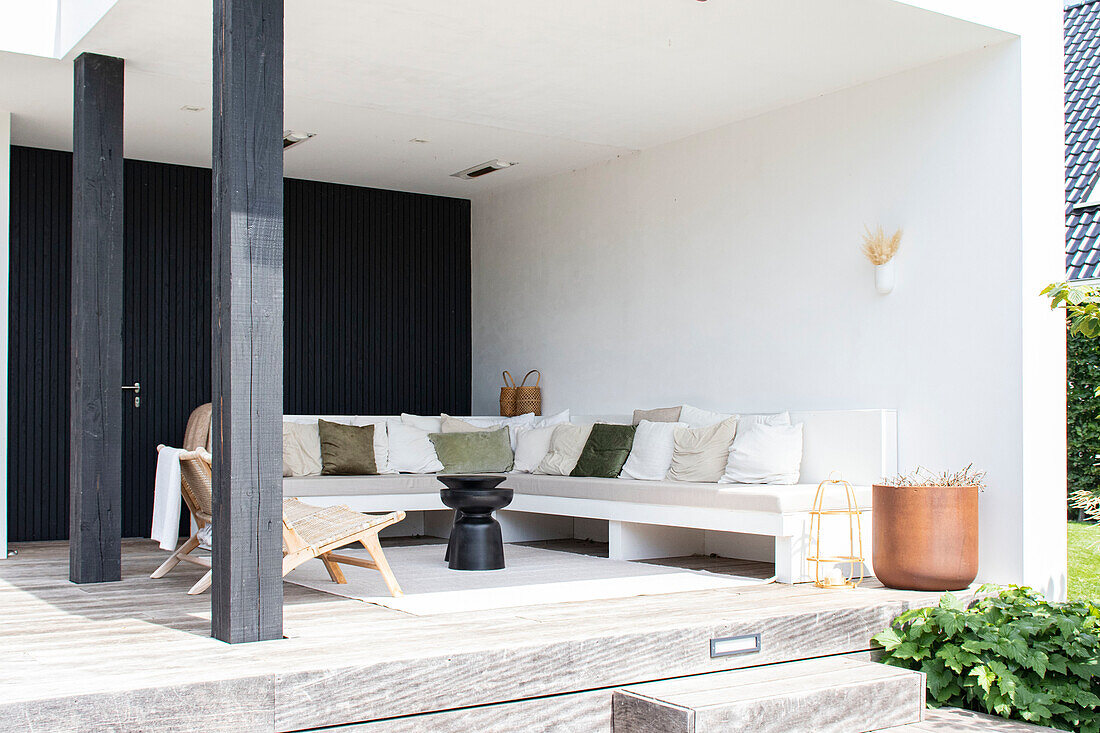 Modern covered terrace with lounge seating area and white and green pillows