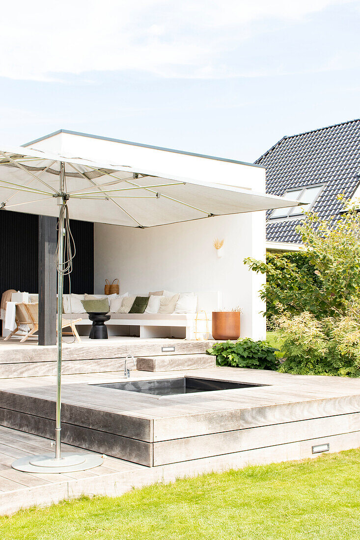 Modern terrace with sunken hot tub and umbrella in the garden