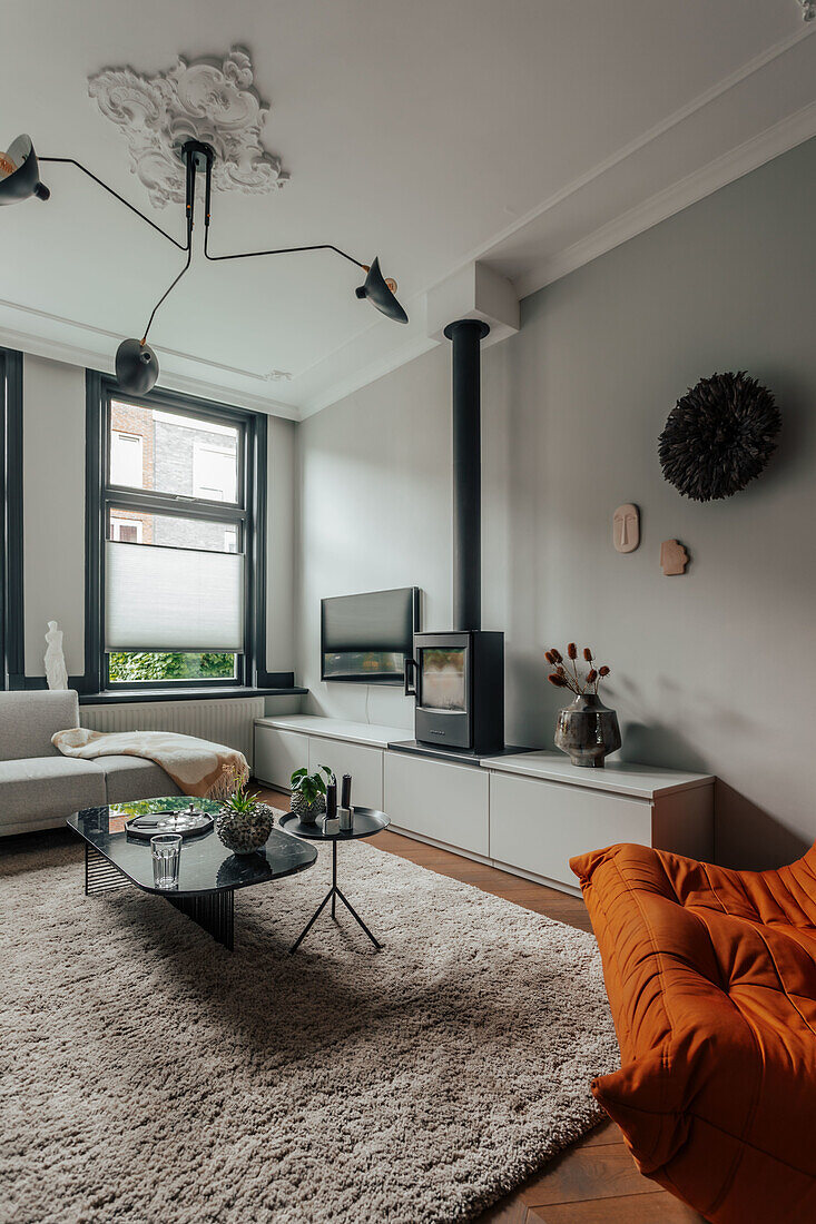 Modern living room with fireplace, orange armchair and large rug