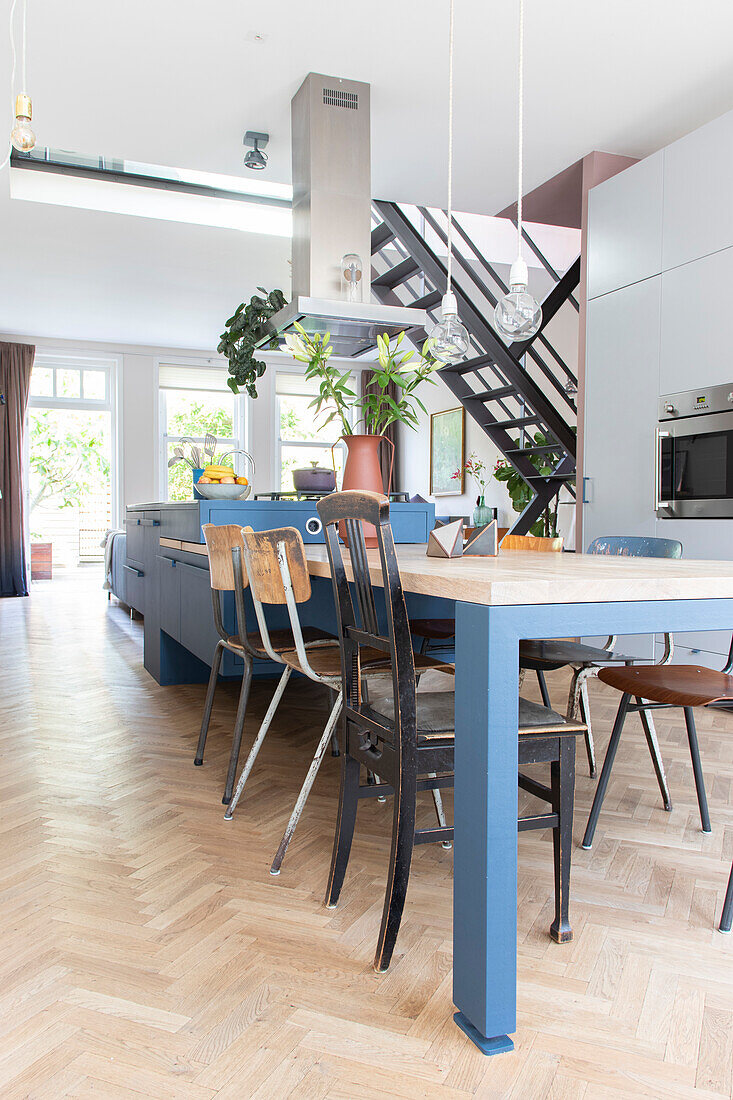 Open-plan kitchen with blue elements and industrial-style chairs