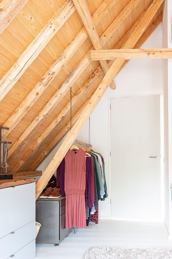 Clothes rack in the attic with exposed wooden beams