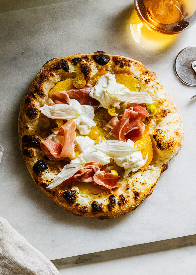 Neapolitanische Pizza mit Ananas, Tomate, Serrano Schinken, Burrata und Blütenblättern