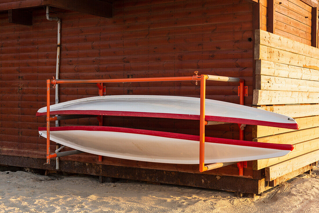 Red and white canoes on rack at shed\n