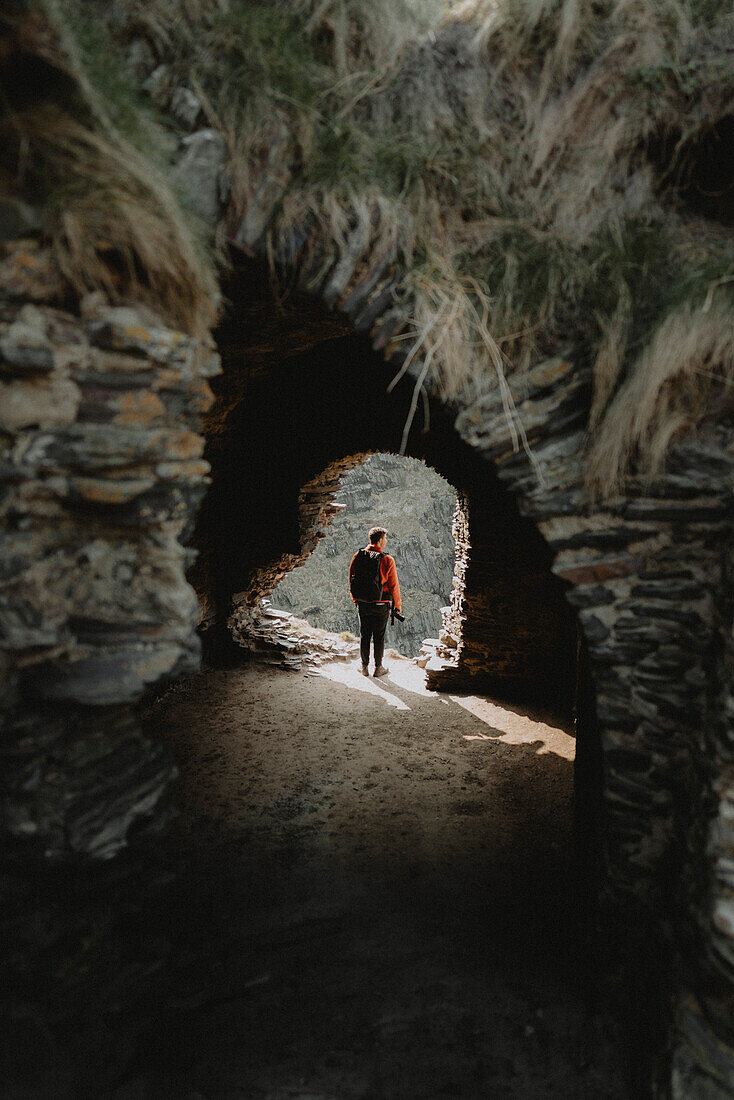 Young man in archway exploring abandoned castle, Findlater, Aberdeenshire, Scotland\n