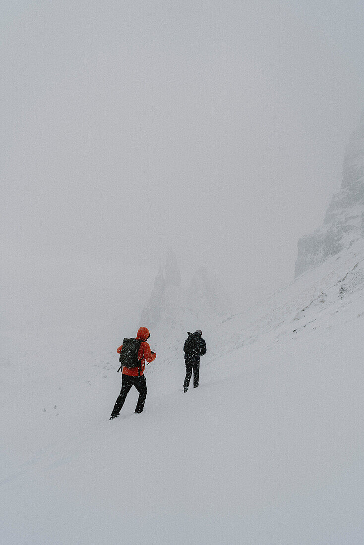 Hikers climbing snow covered mountain, Old Man of Storr, Isle of Skye, Scotland\n