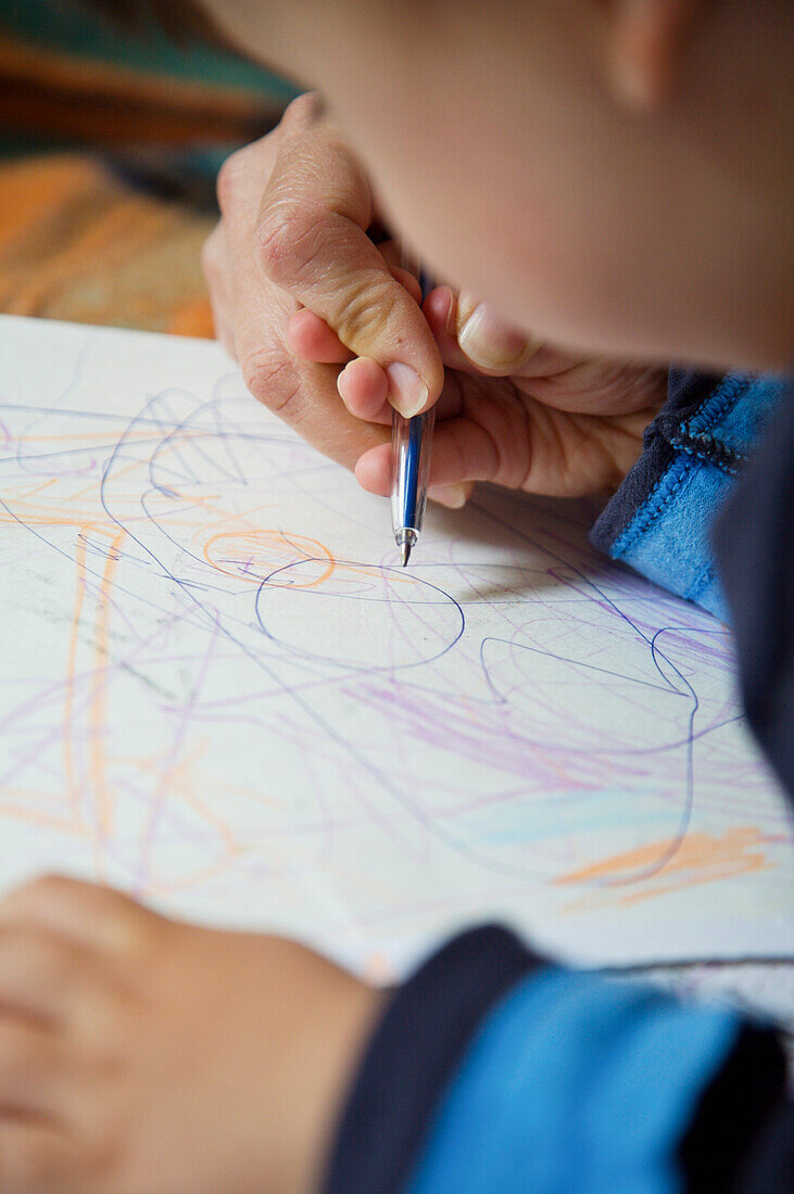 Close up of young boy drawing with color pencil\n