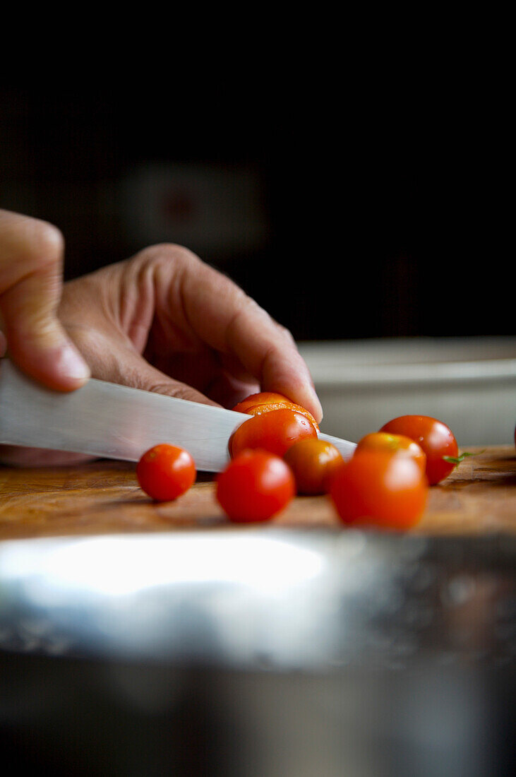 Man's hands cutting cherry tomatoes\n