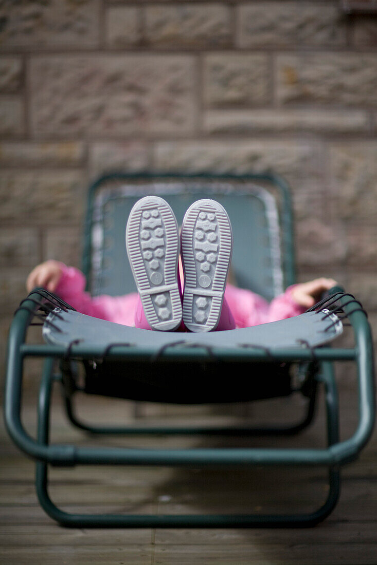 Young girl lying on sun lounger\n