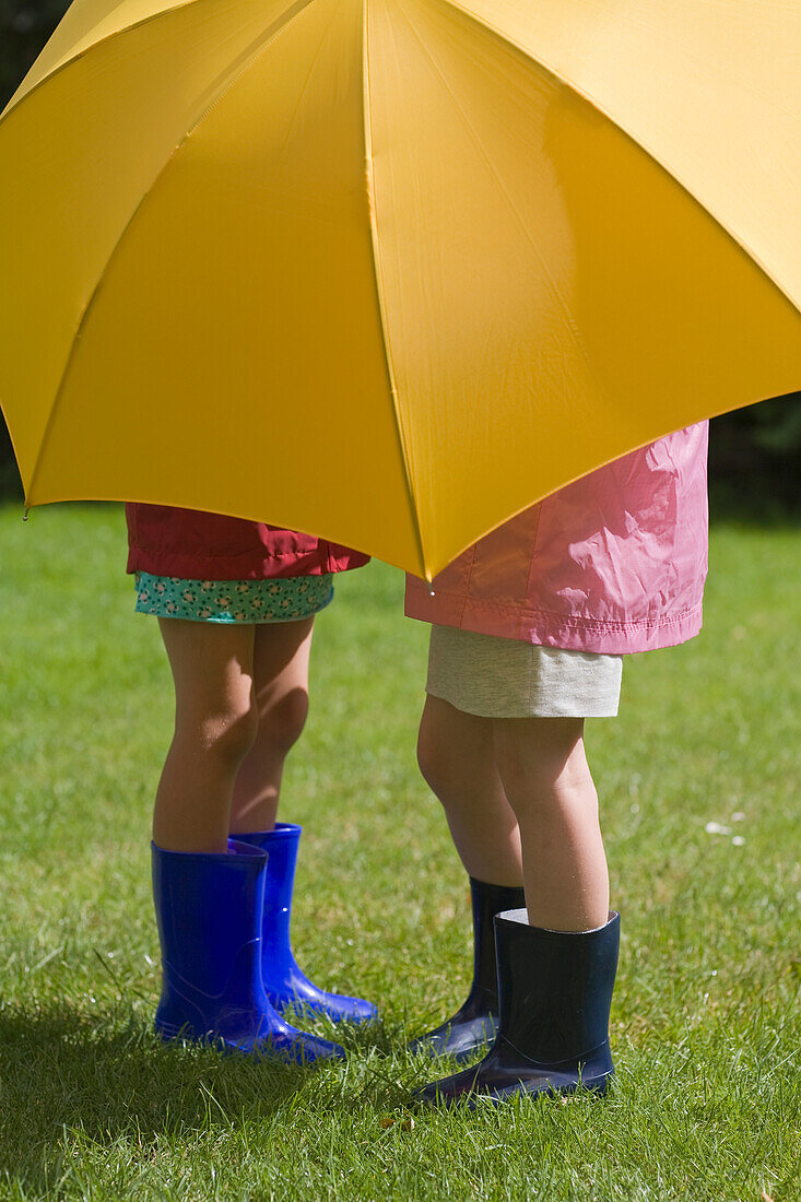 Zwei junge Mädchen unter gelbem Regenschirm