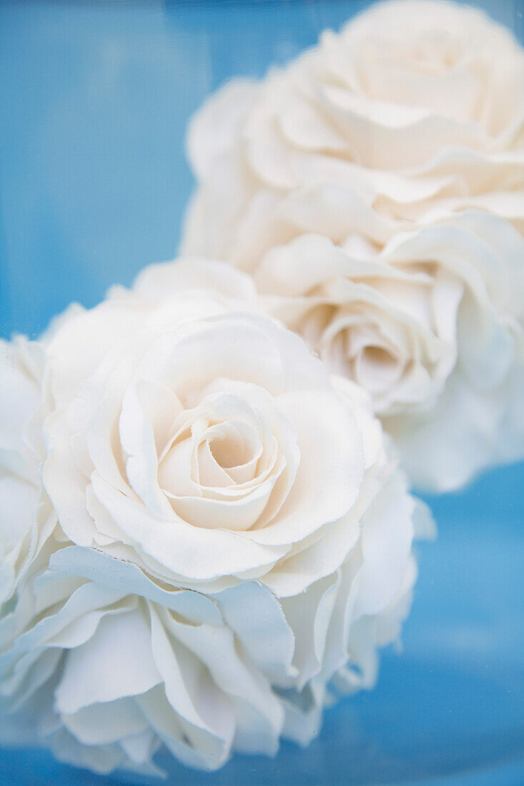 Extreme close up of two fabric white roses\n