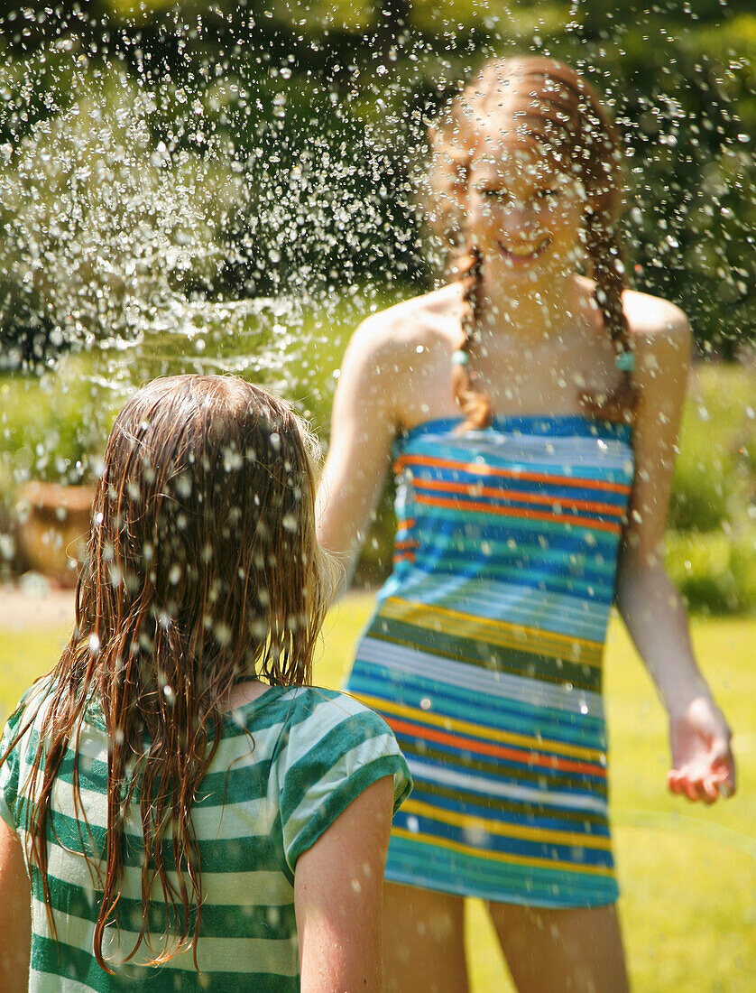 Portrait eines Teenagers, der ein Mädchen mit Wasser besprüht