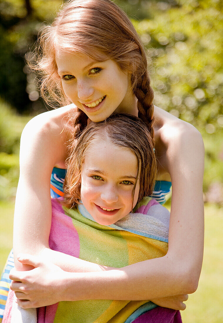 Teen girl hugging sister and drying her off\n