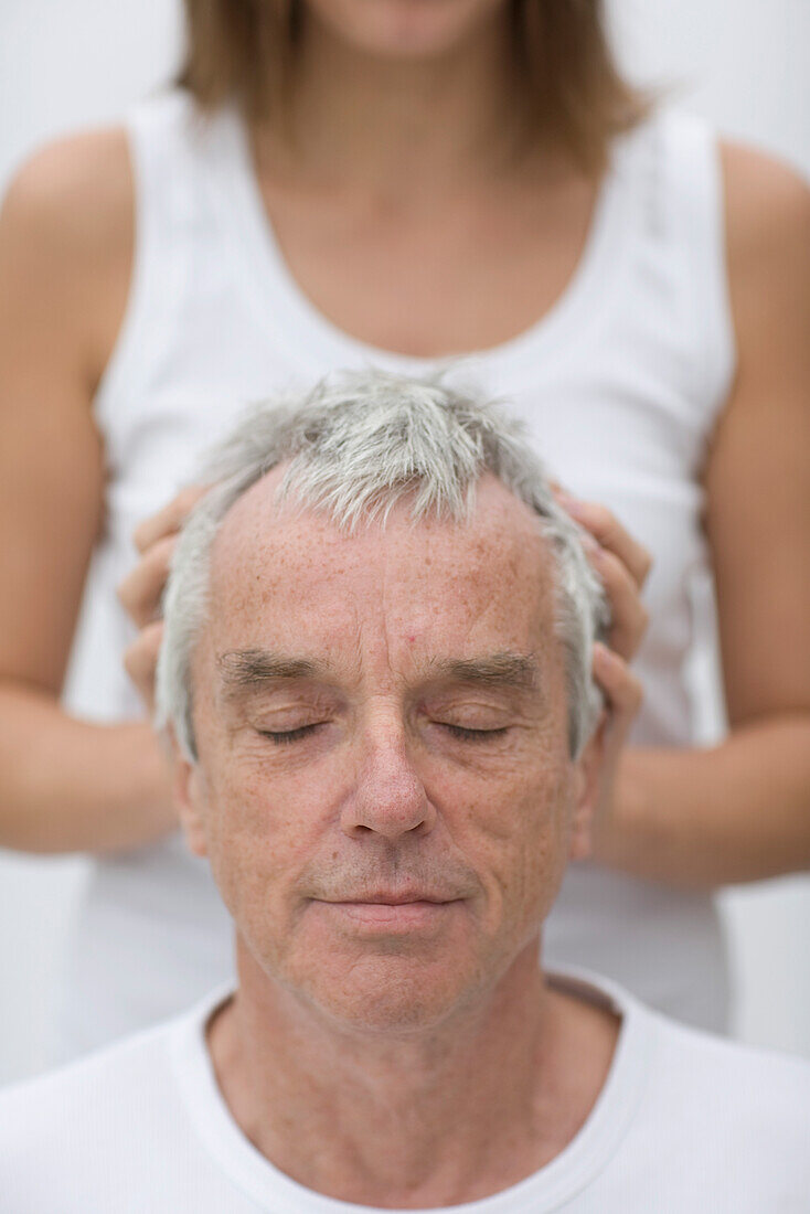 Nahaufnahme eines grauhaarigen Mannes bei einer Kopfmassage