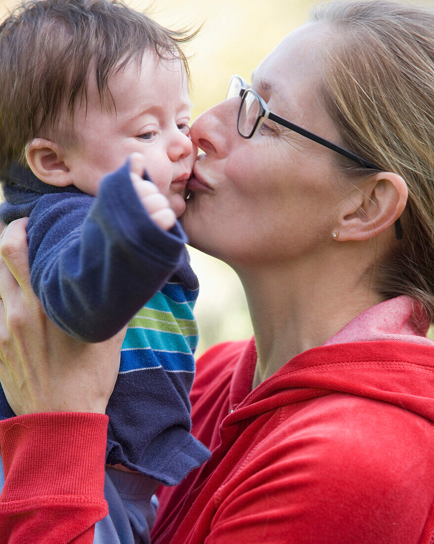 Close up of a woman kissing a little boy\n
