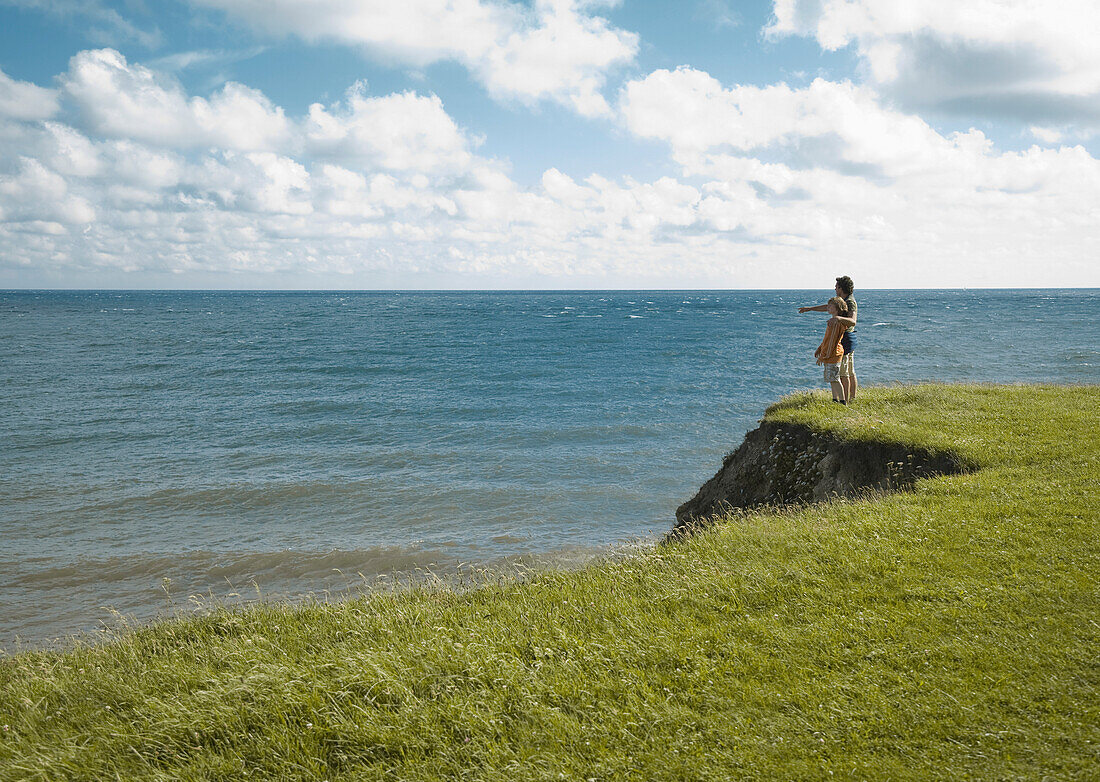 Vater und Sohn stehen am Rande einer Klippe und bewundern den Ozean