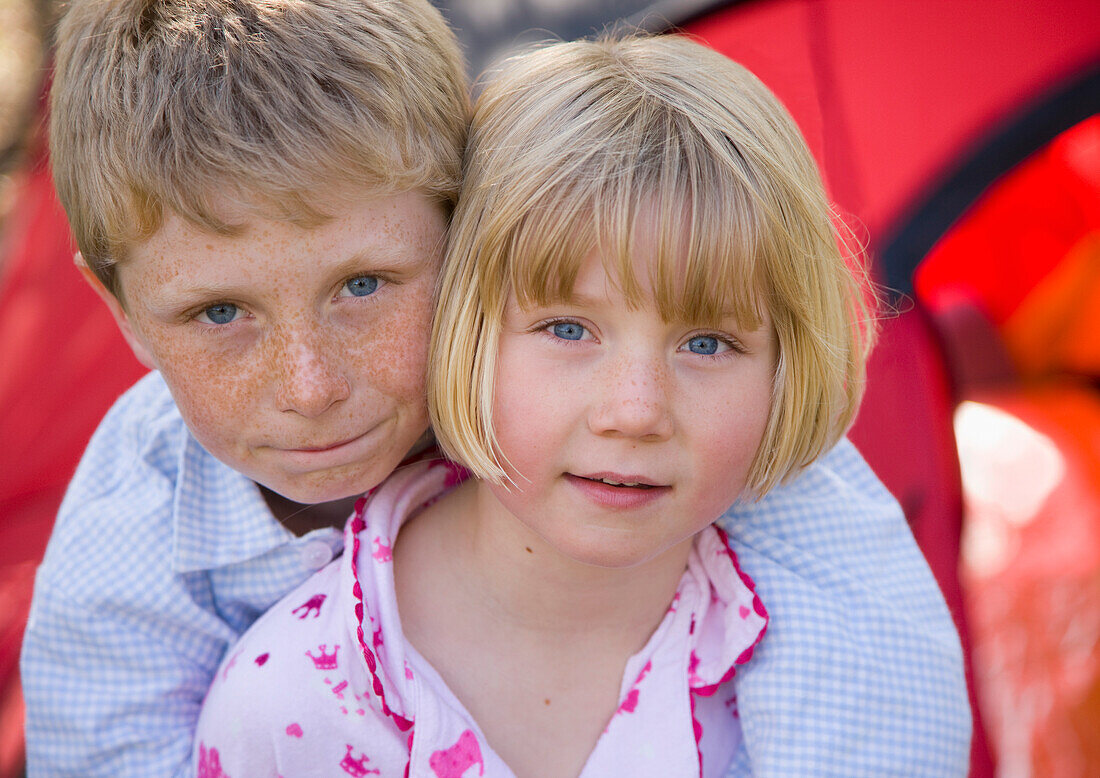 Close up of boy and girl embracing outside tent\n