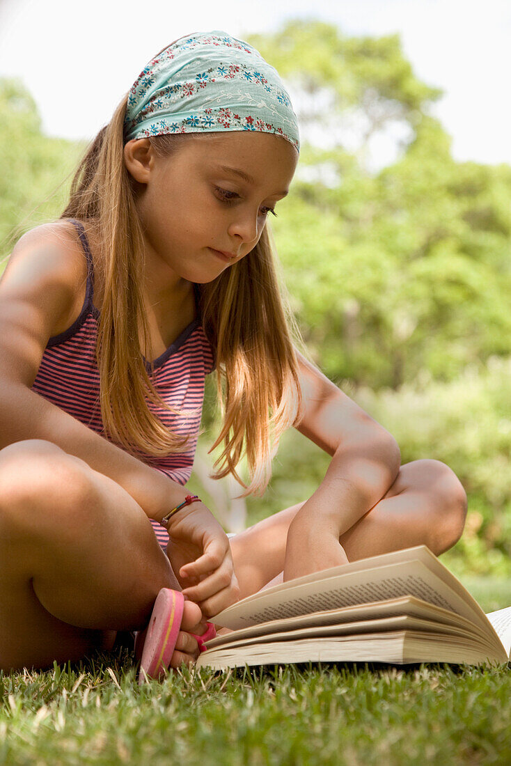 Portrait eines jungen Mädchens, das im Schneidersitz sitzt und ein Buch liest