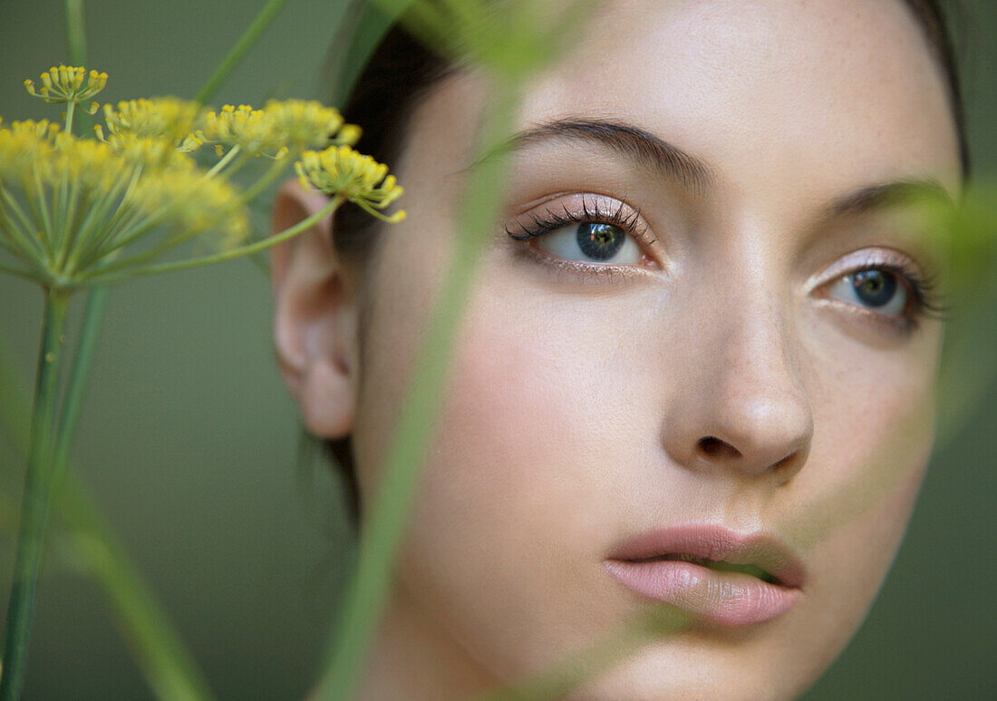 Young beautiful woman lost in thought with yellow flower\n