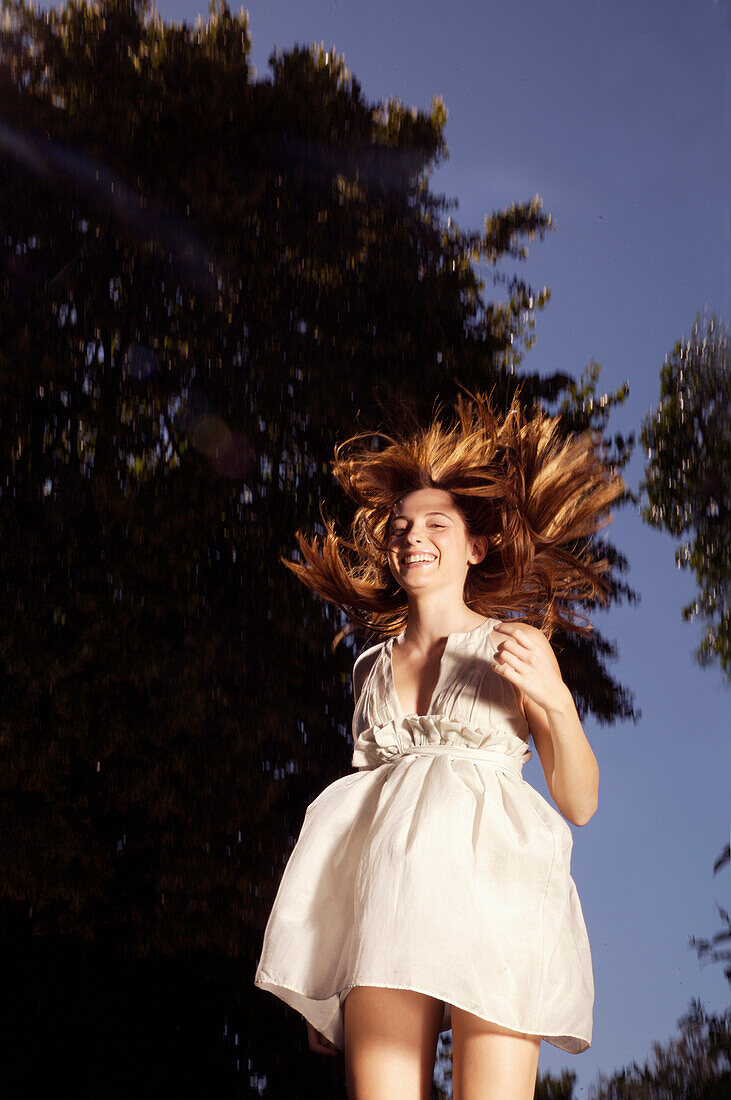 Laughing young woman leaping mid air from trampoline\n