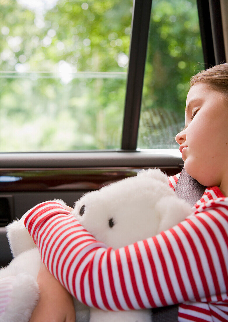 Portrait of young girl sleeping and cuddling teddy bear\n