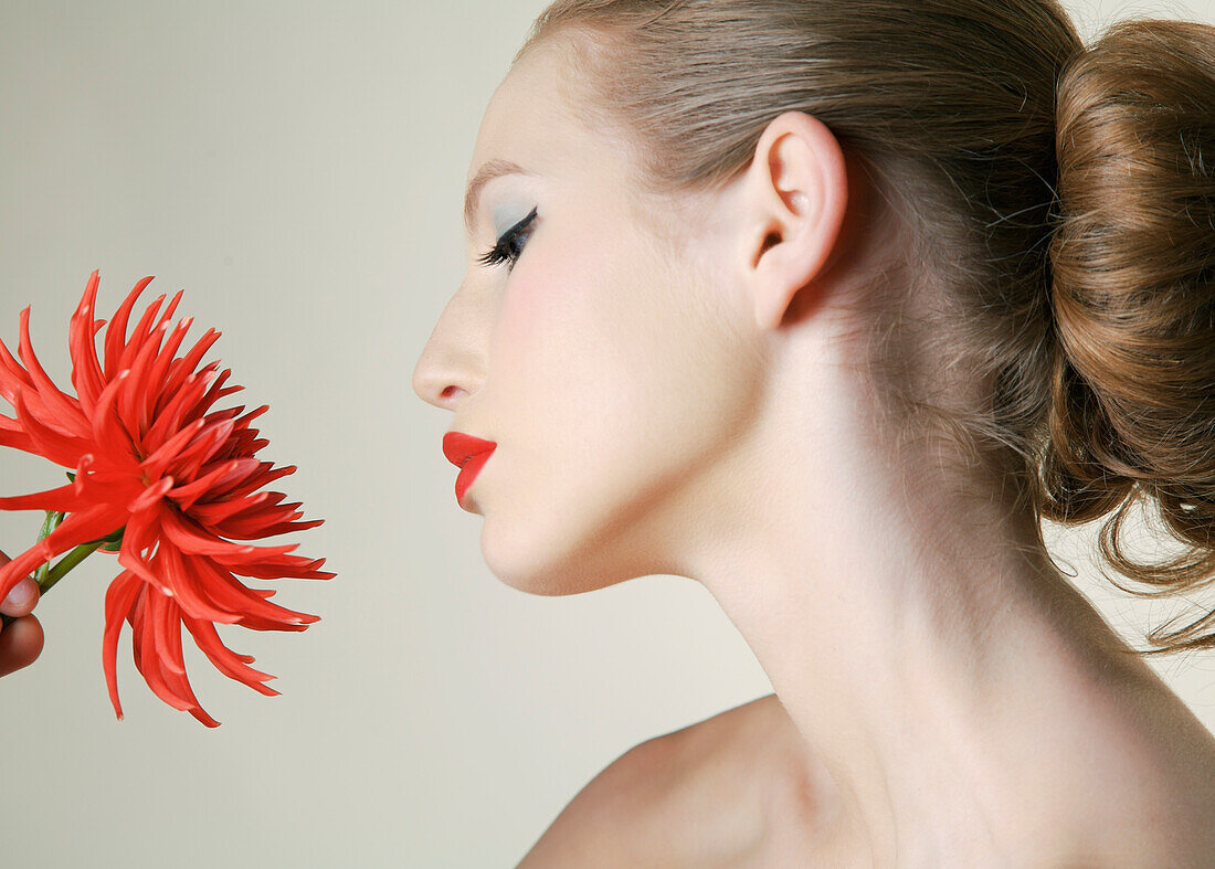 Young woman holding red dahlia\n