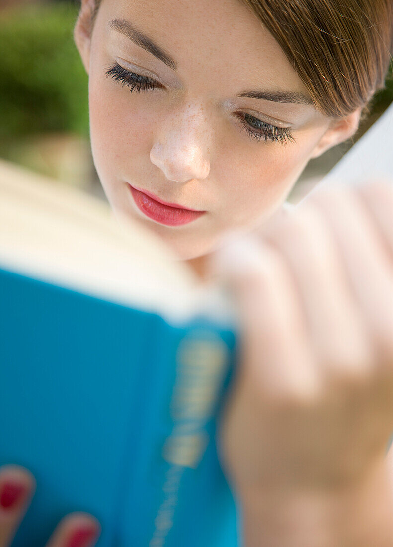 Close up of a teenaged girl reading a book\n