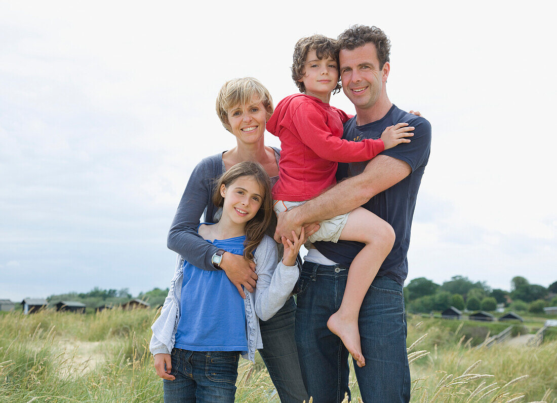 Portrait einer Familie am Strand stehend lächelnd