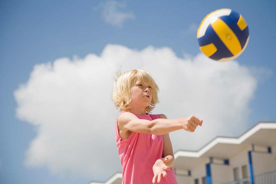 Blonde boy playing volleyball\n