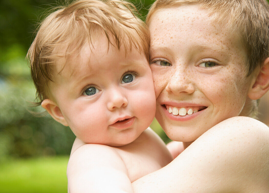 Close up of a young boy holding his baby brother\n
