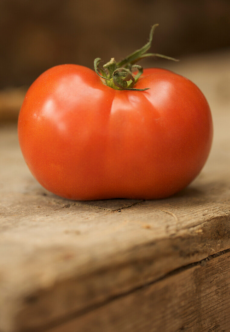 Nahaufnahme einer roten Strauchtomate auf einer Holzfläche