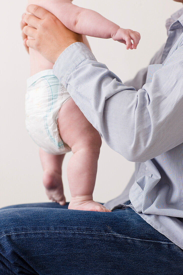 Mann sitzend mit neugeborenem Baby auf dem Schoß