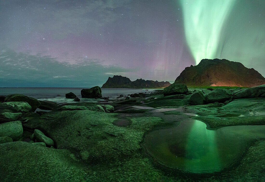 Das grüne Licht der Aurora Borealis (Nordlicht) leuchtet über den Bergen und dem Strand von Uttakleiv, Vestvagoy, Lofoten Inseln, Nordland, Norwegen, Skandinavien, Europa
