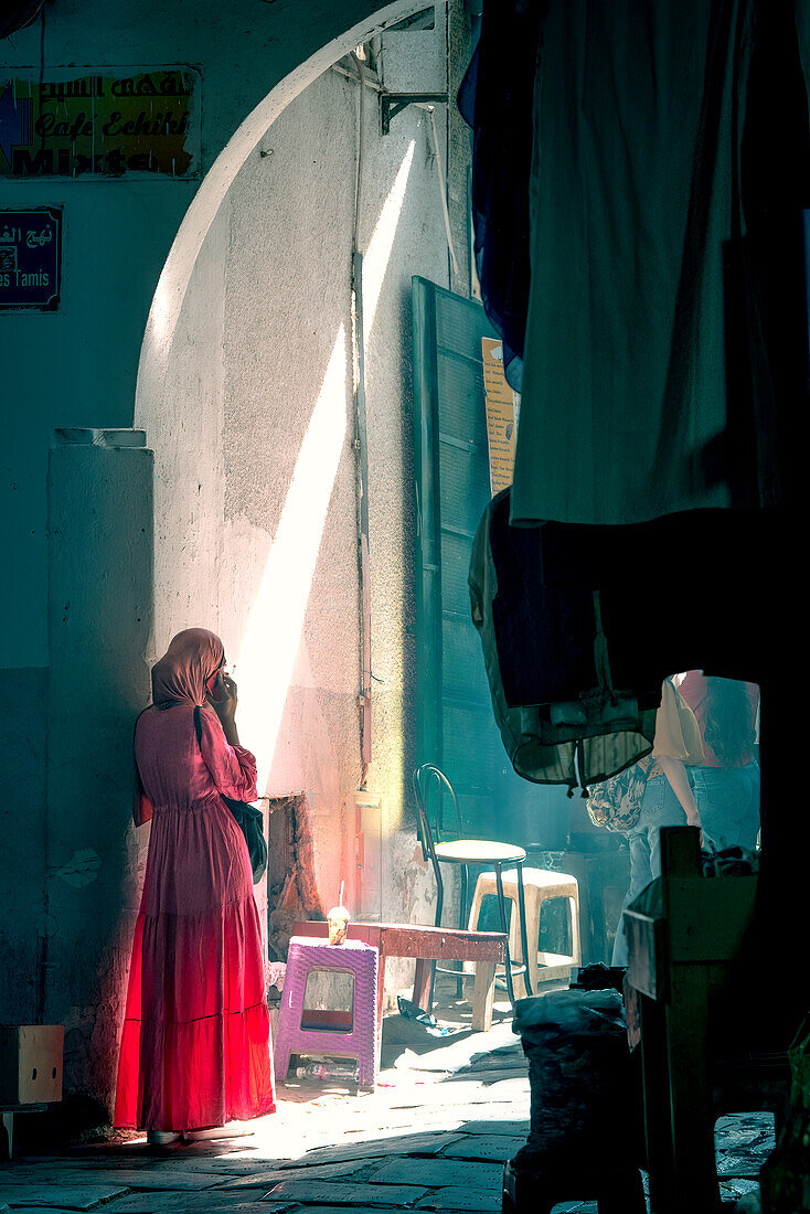 A local in traditional dress stands in the maze-like medina of Tunis, Tunisia, North Africa, Africa\n