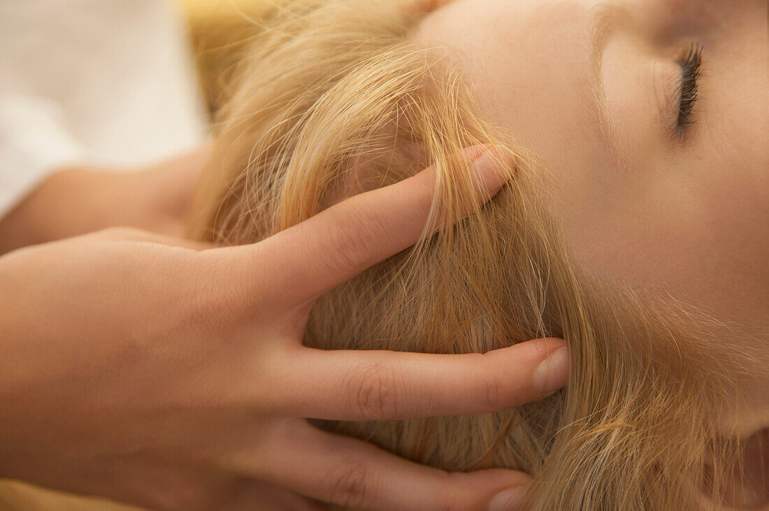 Extreme close up of woman head receiving scalp massage\n