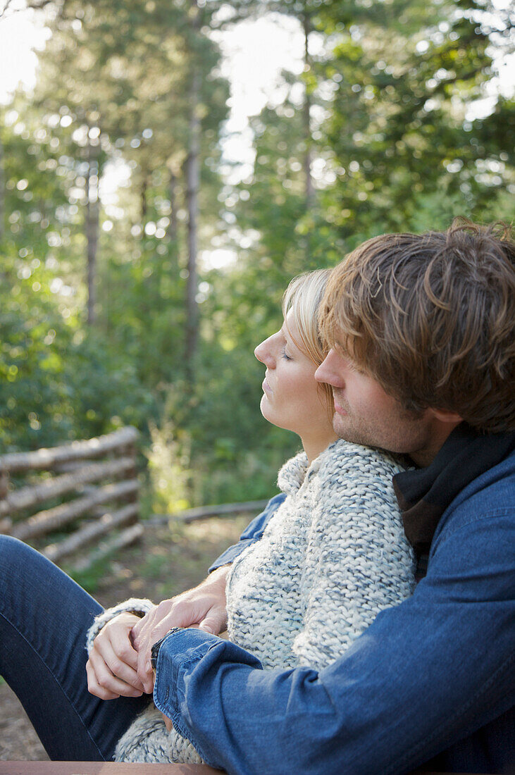 Profil eines jungen Paares sitzend und sich umarmend