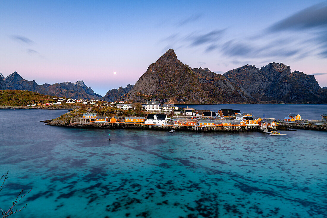 Sunrise over Olstind mountain and fishing village of Sakrisoy overlooking the cold blue sea, Lofoten Islands, Nordland, Norway, Scandinavia, Europe\n