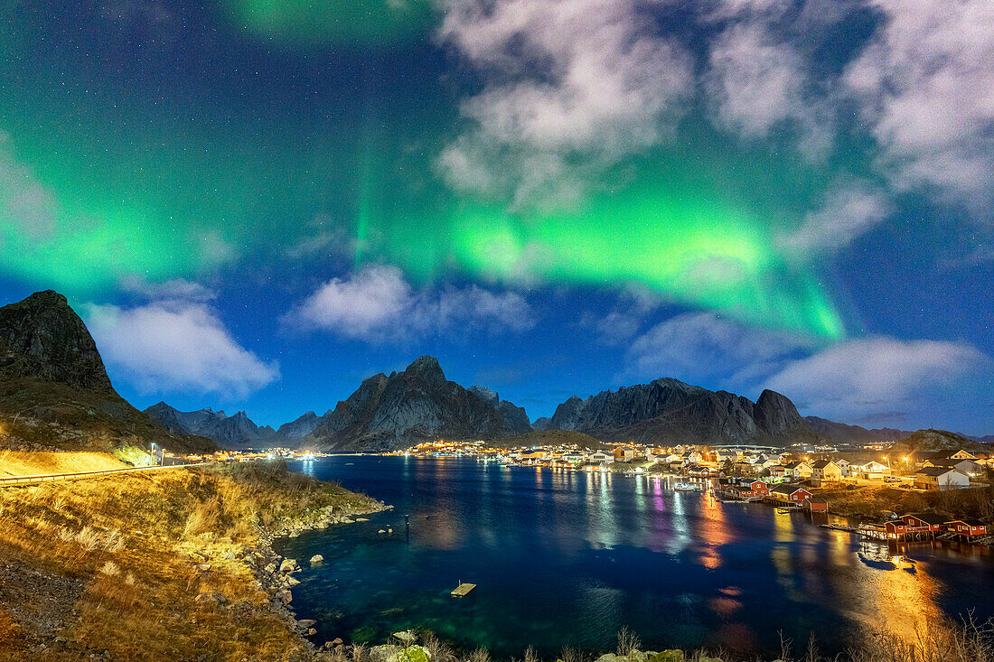 Beleuchteter Hafen von Reine unter den hellen grünen Lichtern der Aurora Borealis (Nordlichter), Lofoten Inseln, Nordland, Norwegen, Skandinavien, Europa