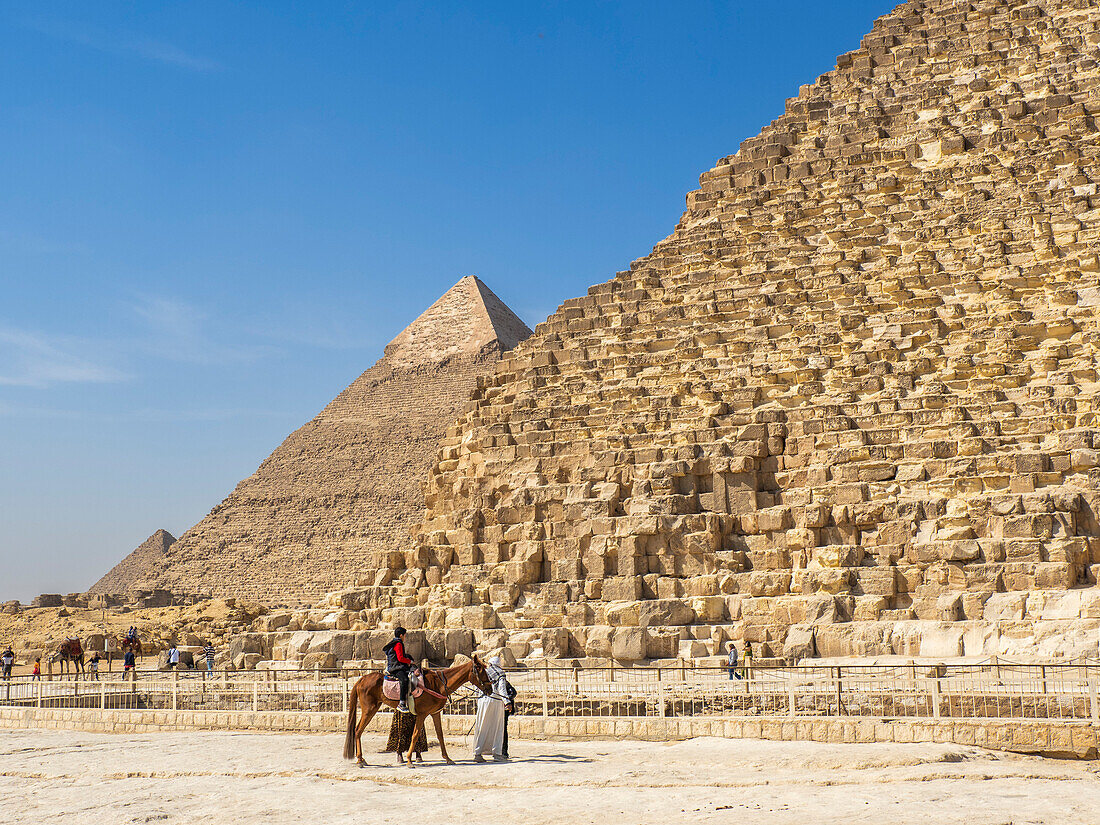 Touristen auf Kamelritt vor der Großen Pyramide von Gizeh, dem ältesten der Sieben Weltwunder, UNESCO-Weltkulturerbe, Gizeh, bei Kairo, Ägypten, Nordafrika, Afrika