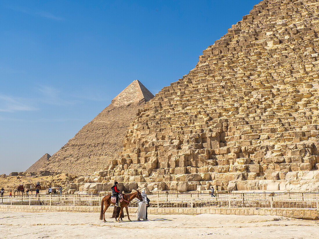 Tourists on camel ride in front of the Great Pyramid of Giza, the oldest of the Seven Wonders of the World, UNESCO World Heritage Site, Giza, near Cairo, Egypt, North Africa, Africa\n