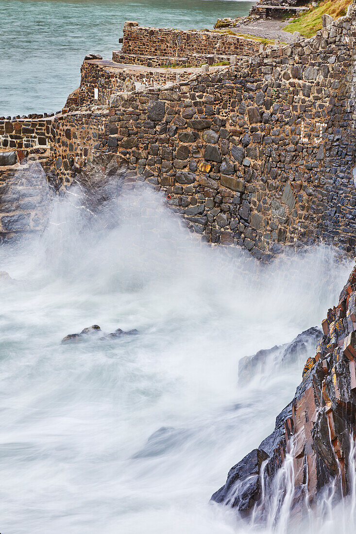 On a rising tide, evening surf pounds the historic harbour wall at Hartland Quay, on the Atlantic coast of Devon, England, United Kingdom, Europe\n