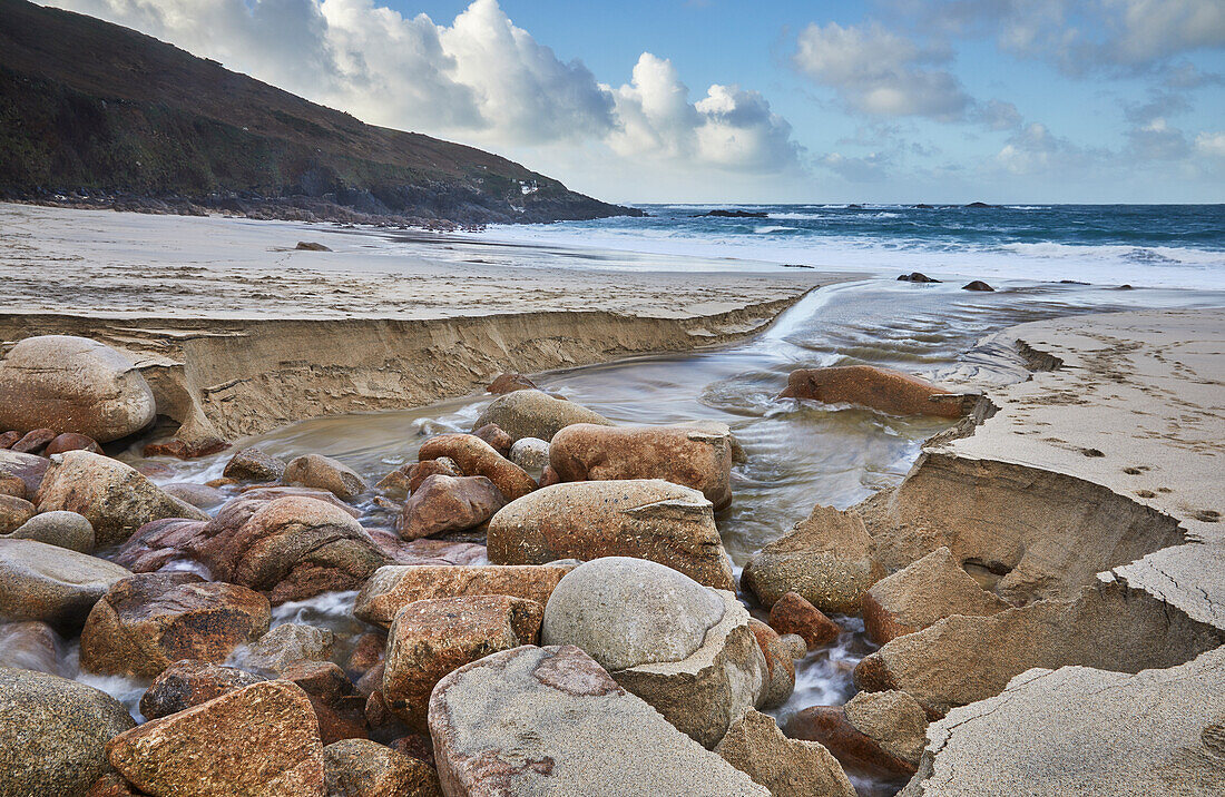 Ein Bach durchschneidet Sand und Felsen auf seinem Weg ins Meer, Portheras Cove, eine abgelegene Bucht an der Atlantikküste, bei Pendeen, im äußersten Westen Cornwalls, England, Vereinigtes Königreich, Europa