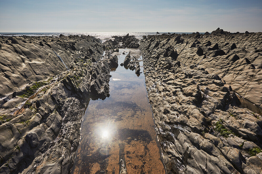 Ein glitzernder, von der Sonne beschienener Pool an der Atlantikküste bei Ebbe, Welcombe Mouth, eine Bucht in der Hartland-Region im Norden Devons, England, Vereinigtes Königreich, Europa