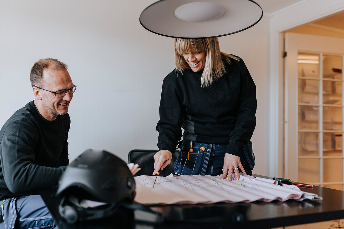 Lächelnde Ingenieure bei der Arbeit an Plänen