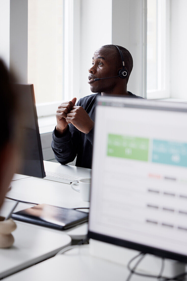 Mature businessman using headset and while sitting in office\n