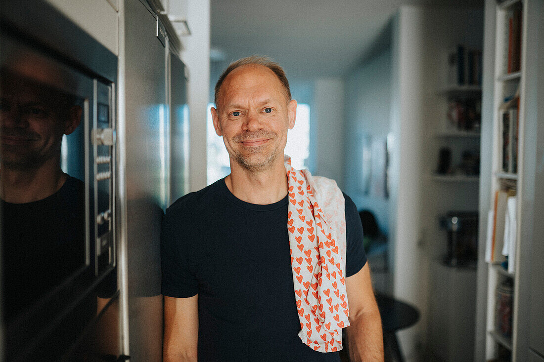 Portrait of smiling mature man doing housework in kitchen\n