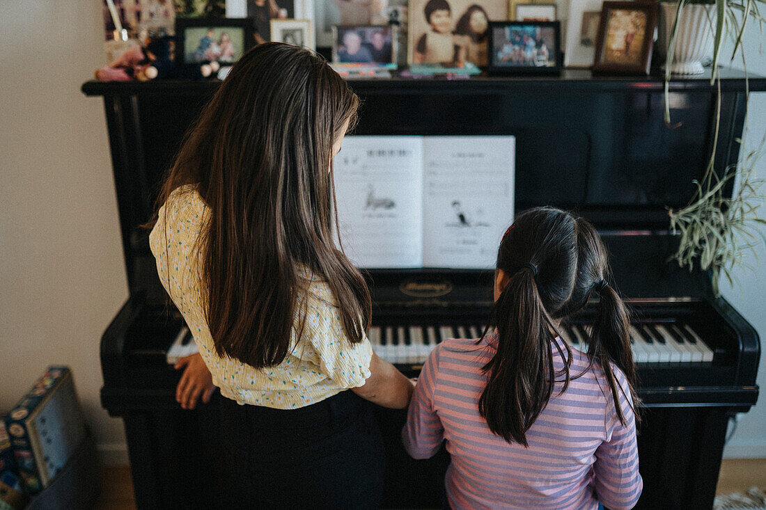 Sisters bonding over playing piano together\n