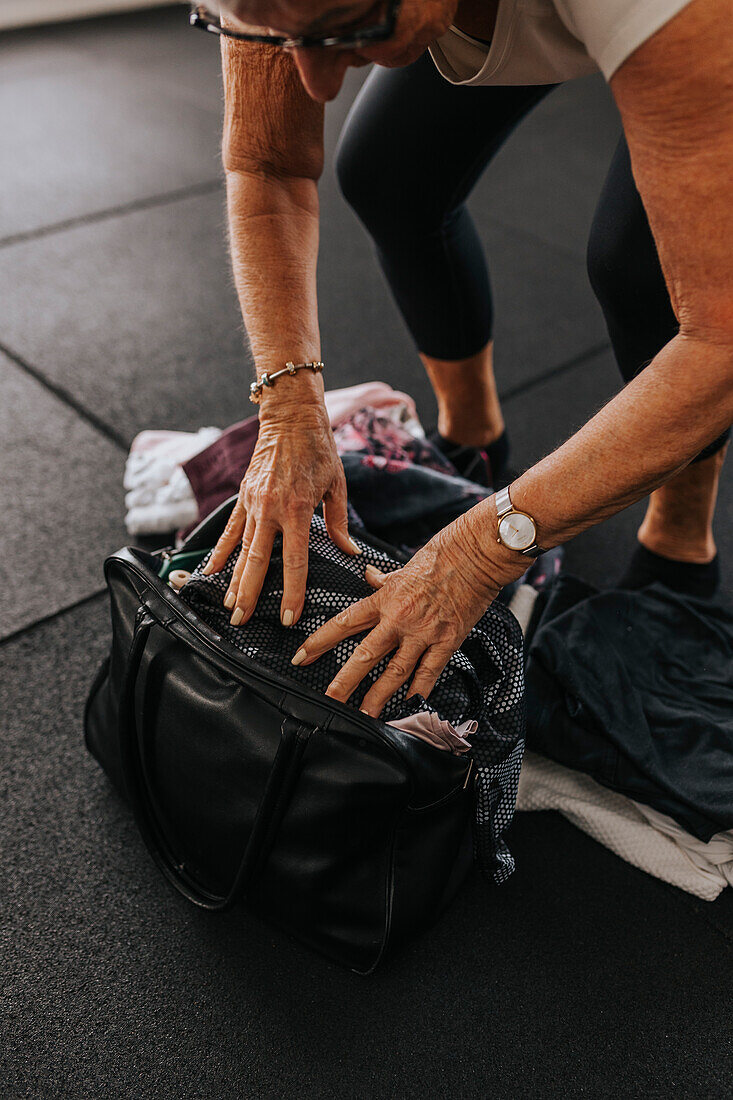 Senior woman packing equipment after workout in gym\n